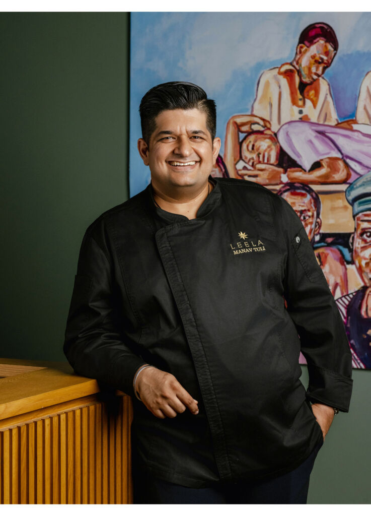 Chef Manav leaning on the counter in front of an oil painting