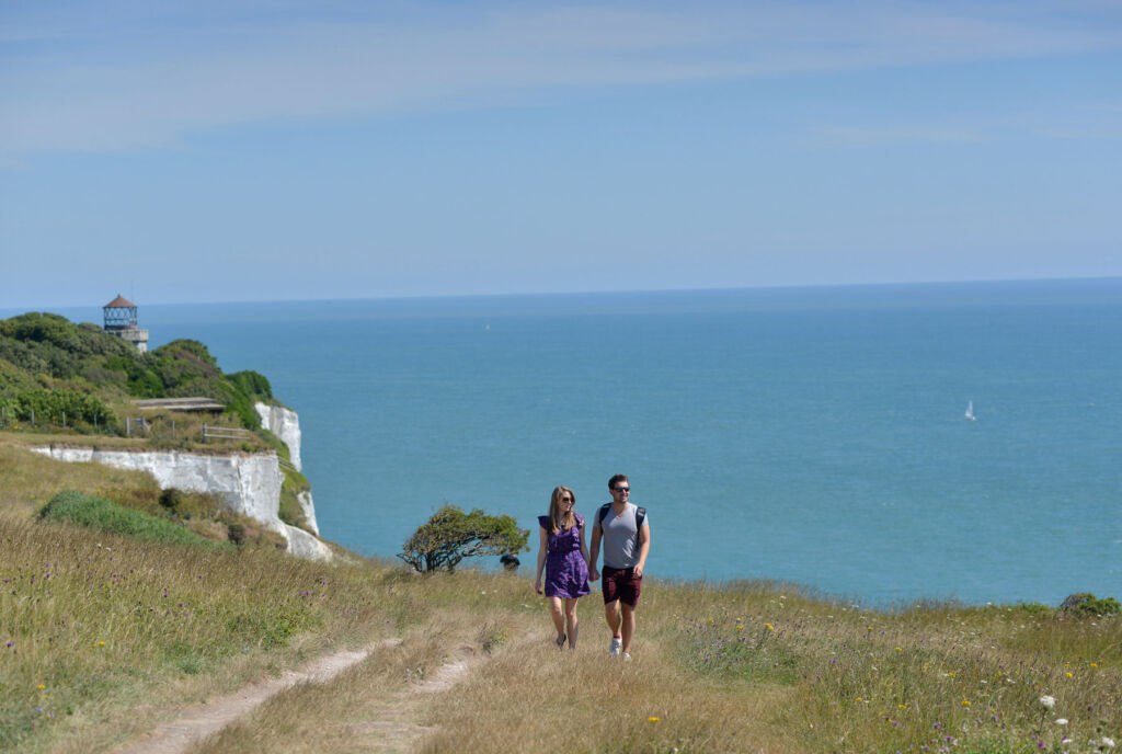A young couple walking on a path on top of the cliffs