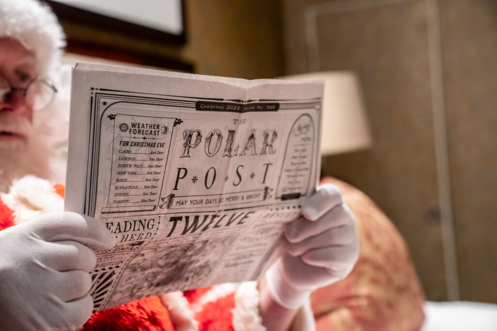 Santa reading a copy of the Polar Post before heading back to the North Pole