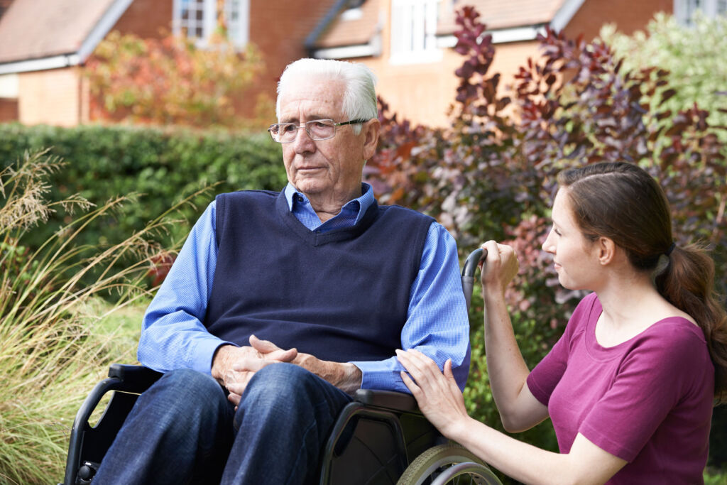 A young woman talking to an older person in a wheelchair