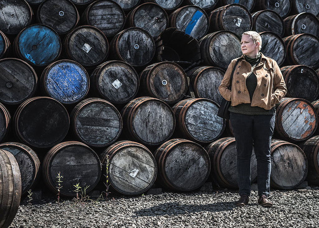 Emma outdoors standing in front of a stack of empty casks
