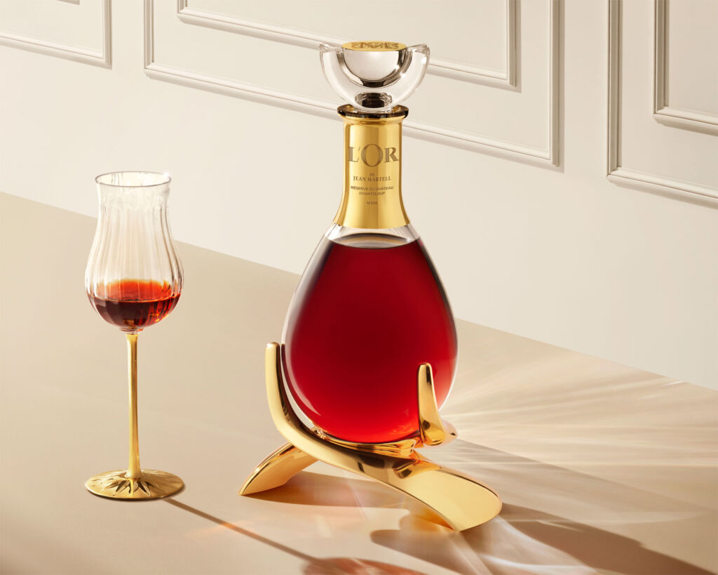 An image showing the beautiful gold and crystal decanter next to a part filled matching glass