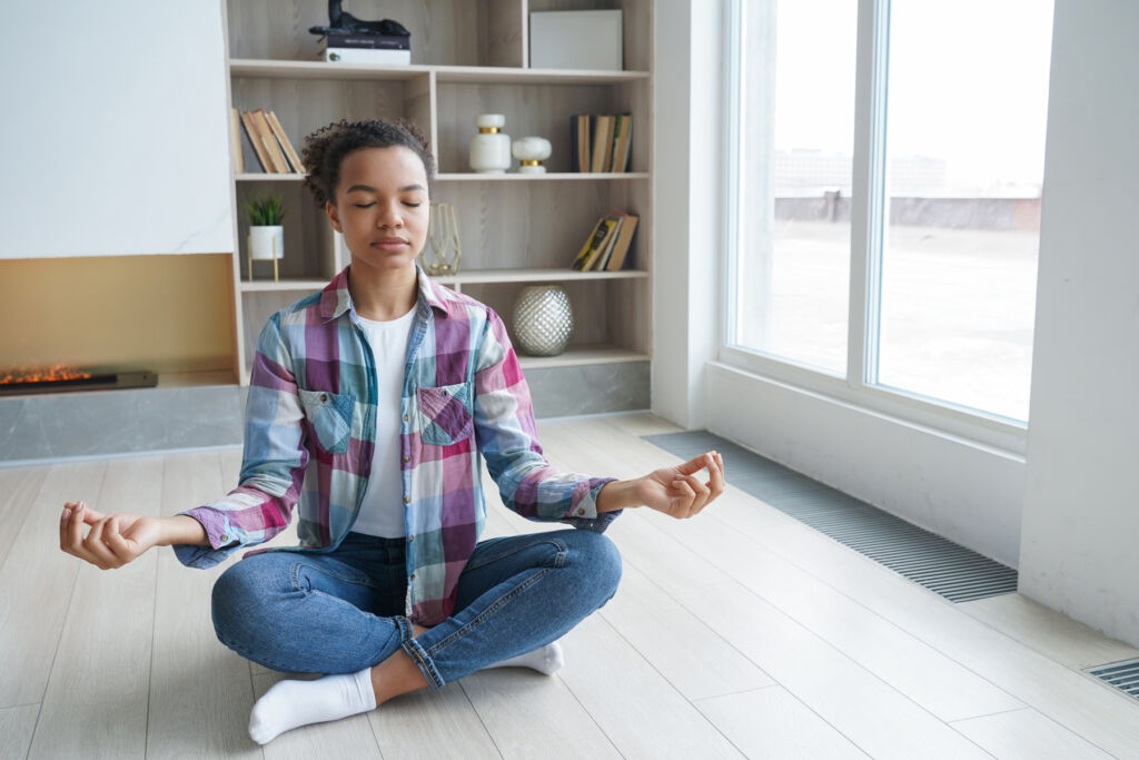 A young woman indoors in a classic meditation pose