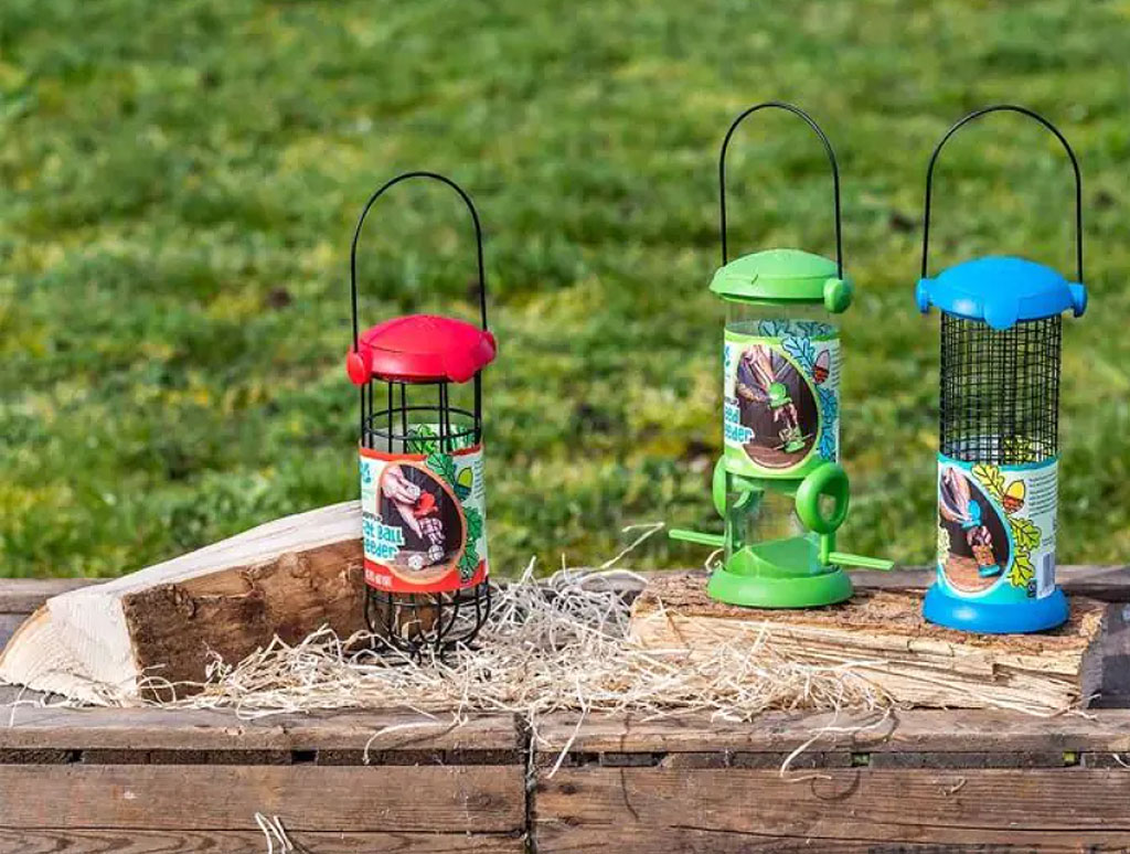 Red, green and blue coloured feeders on a wooden worktop outdoors