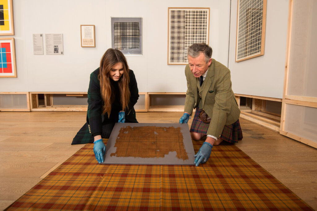 Emma and Peter comparing the world's oldest piece of Tartan with the modern-day version