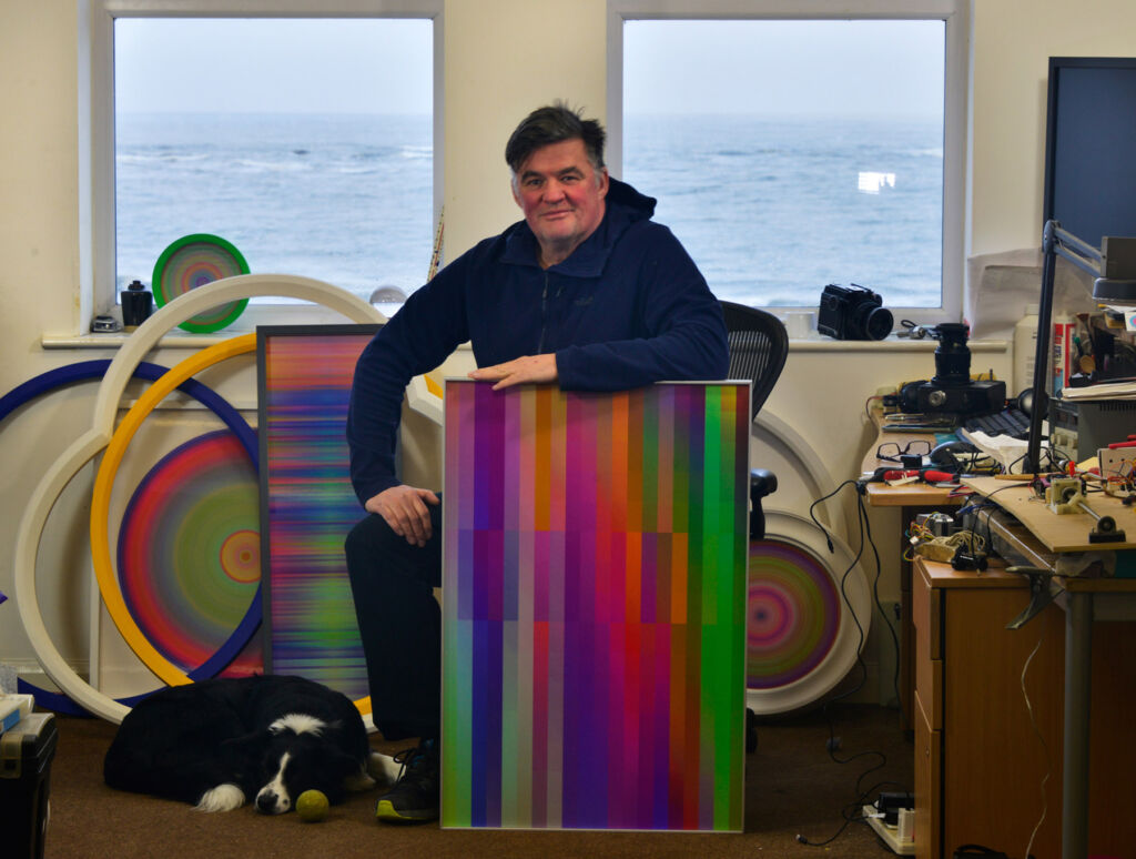 A seated Lawrie Hutcheon with some of his artworks