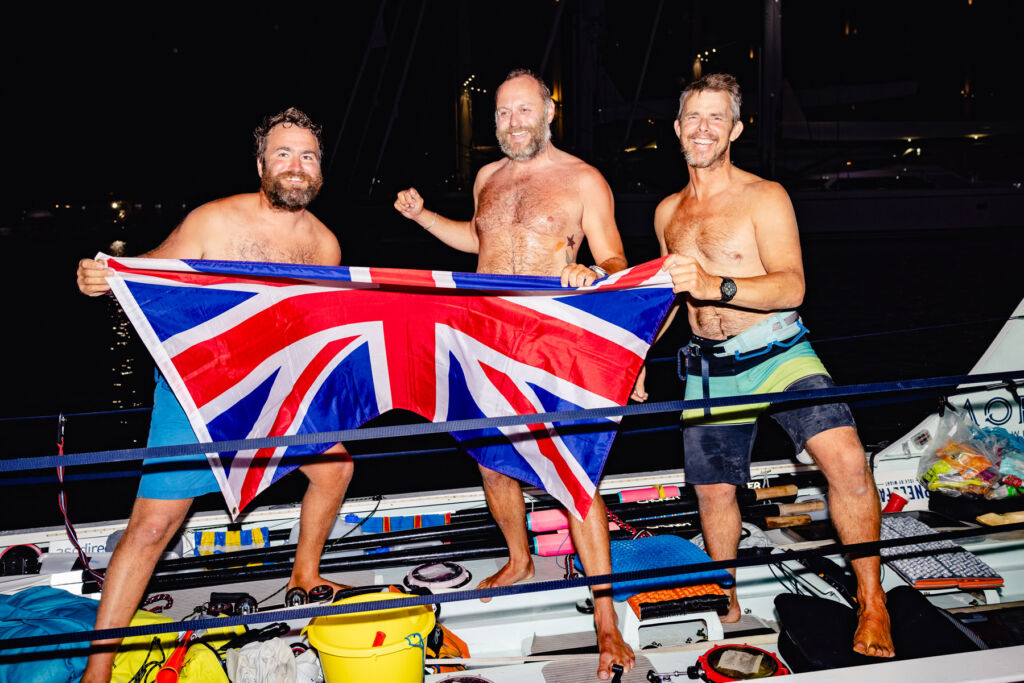 Three ecstatic rowers holding the Union Jack Flag