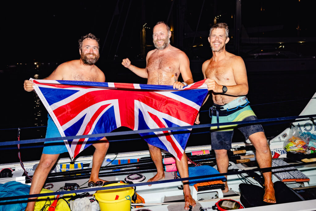 Mermaid Atlantic Team Complete 3,000 Nautical Miles Charity Row 8 Three ecstatic rowers holding the Union Jack Flag