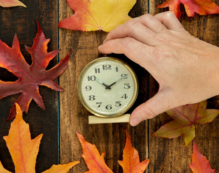 A clock surrounded by autumnal leaves