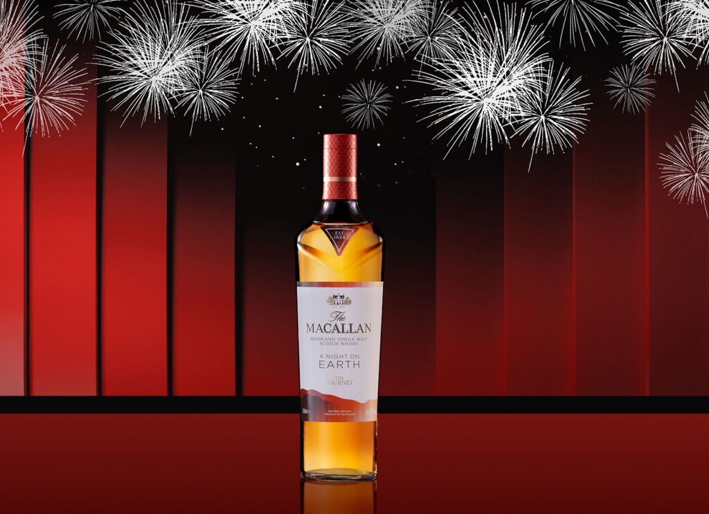 The Macallan A Night On Earth - The Journey  in front of a red curtain with fireworks being set off above it