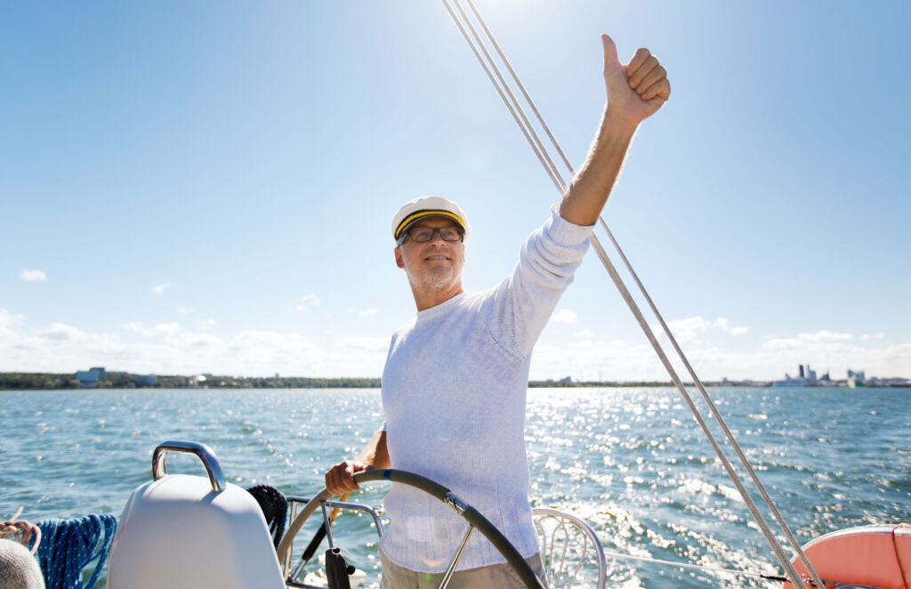 A bearded man, enjoying sailing a chartered yacht