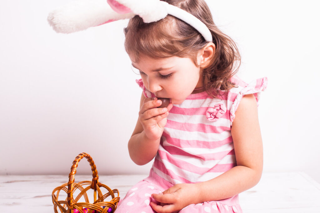 A young girl eating a small Easter egg