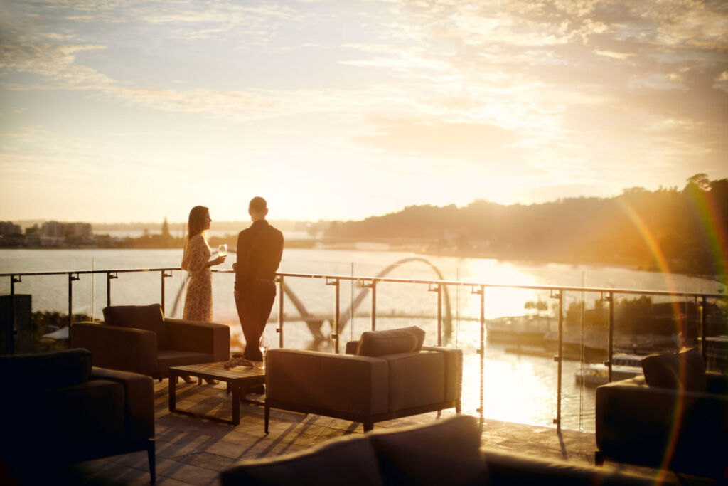 A couple enjoying a drink on the Ritz Carlton Club terrace at sunset