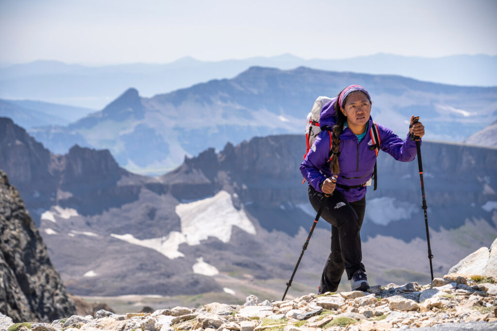 A woman who has reached the top of a mountain using the walking poles