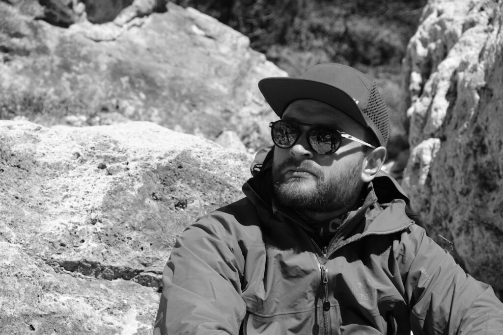 A black and white photograph of James sitting on some rocks