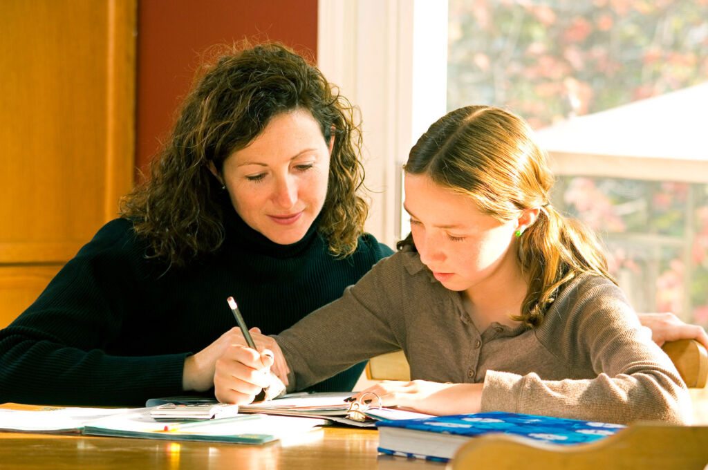 A young girl studying with her mother