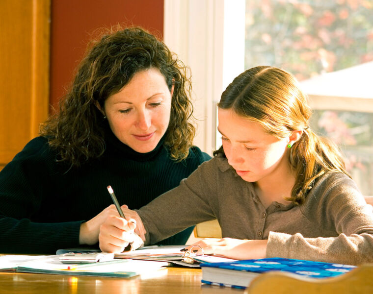 A young girl studying with her mother