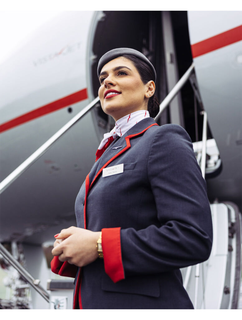 A female attendant waiting for guests by the aircraft entrance