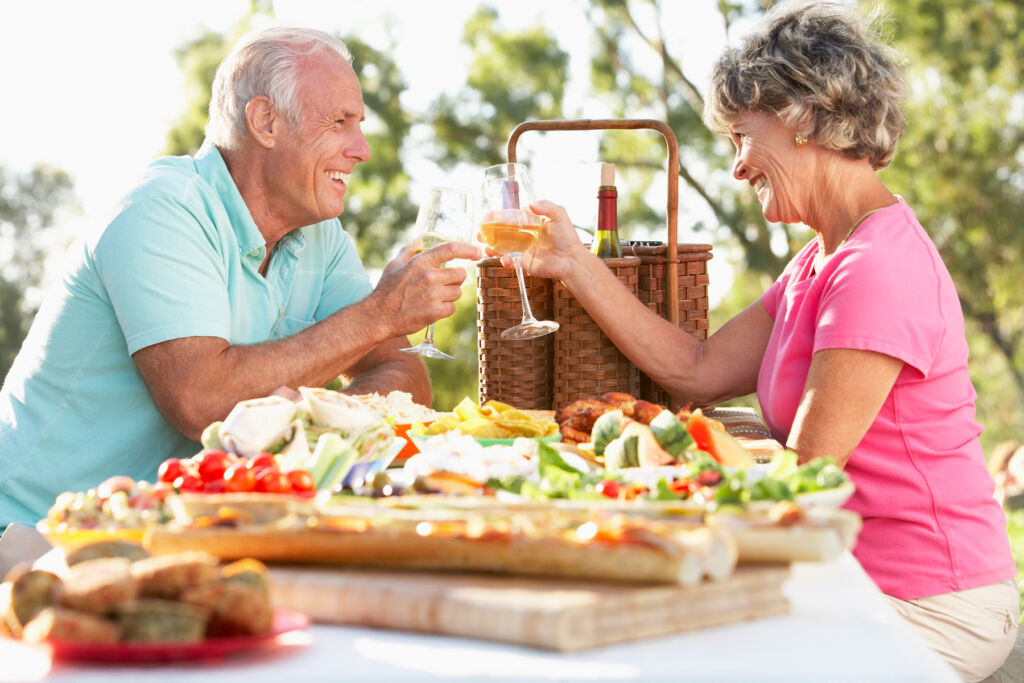 An older couple enjoying food and wine outdoors