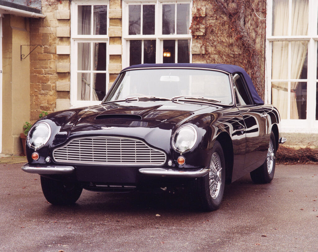 A dark purple DB6 parked outside a home