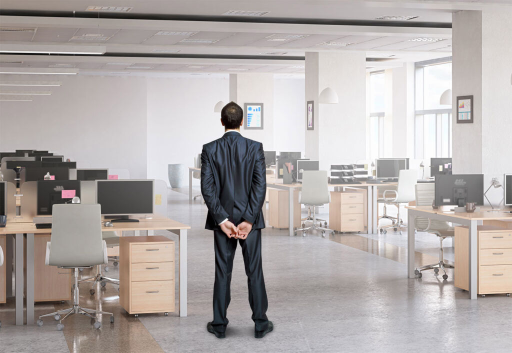 A businessman standing in an empty office with his hands clasped behind his back
