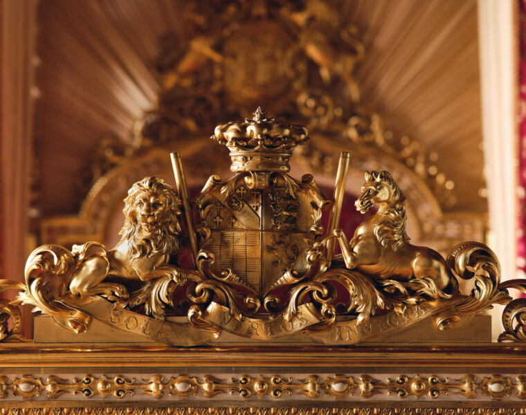 The gilded royal coat of arms on in the foot of the bed