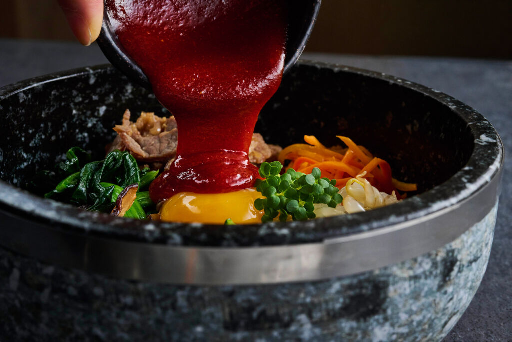 SOOM Brings the Heart of Korean BBQ Culture to London’s Covent Garden 13 A red sauce being poured onto a dish