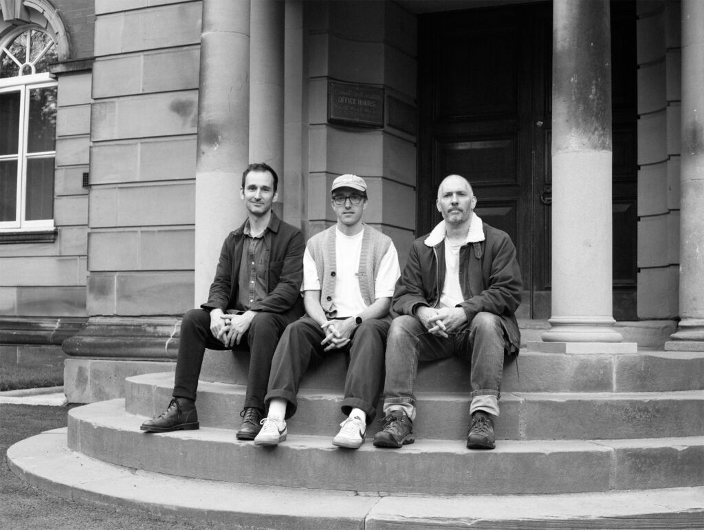 A black and white photograph of Adam, Bert, and Jacob sitting on stone steps