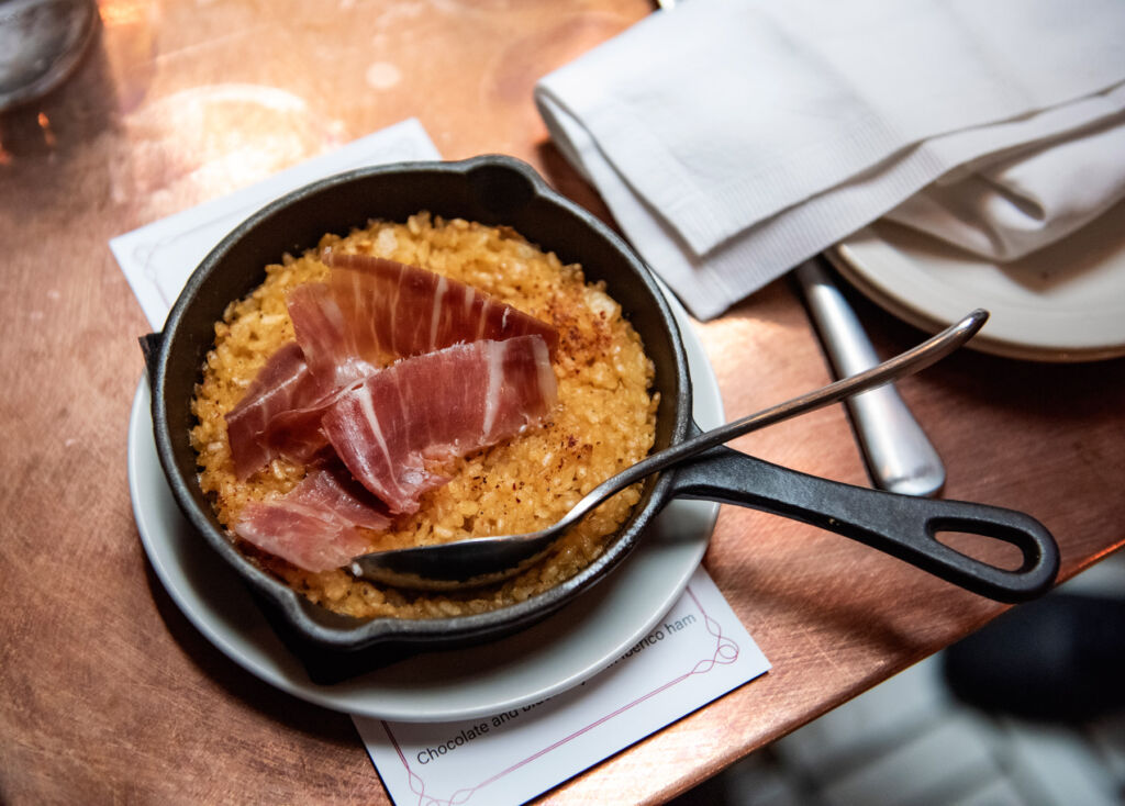Omar Allibhoy Brings the Soul of Ibérico Ham to British Tables 18 Slices of ham on a rice dish inside an iron pan