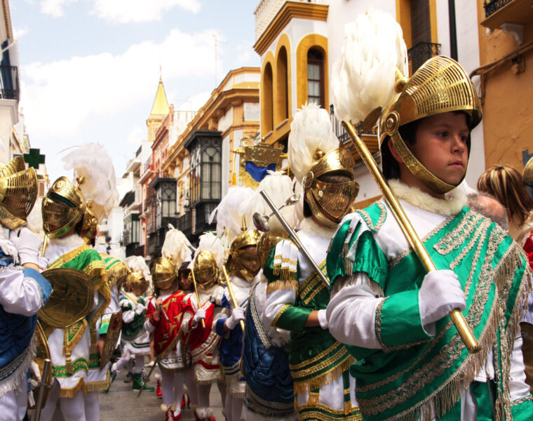 Children wearing traditional costumes parading through a town