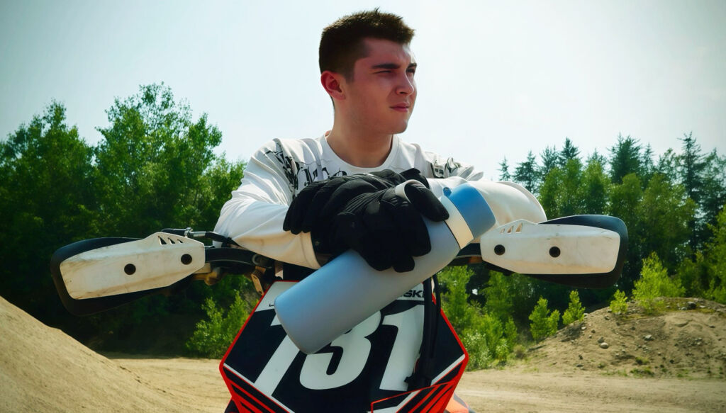A motor-X rider on his bike holding a blue coloured bottle