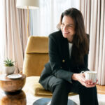 A smiling woman seated and wearing one of the blazers