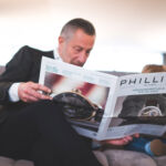 A man sitting on a sofa browsing the auction catalogue